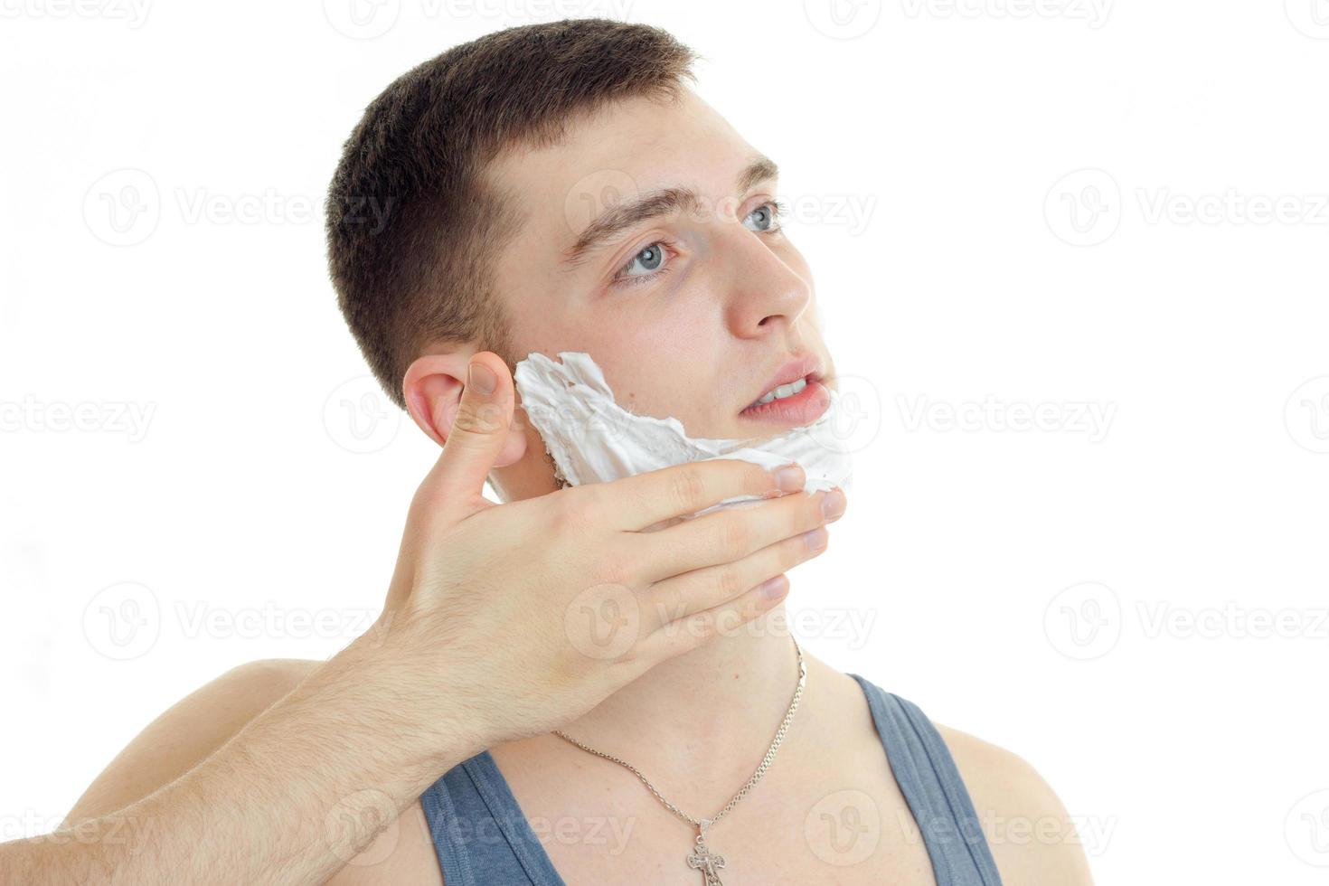 Portrait of a young guy who looks away and putting a beard foam photo