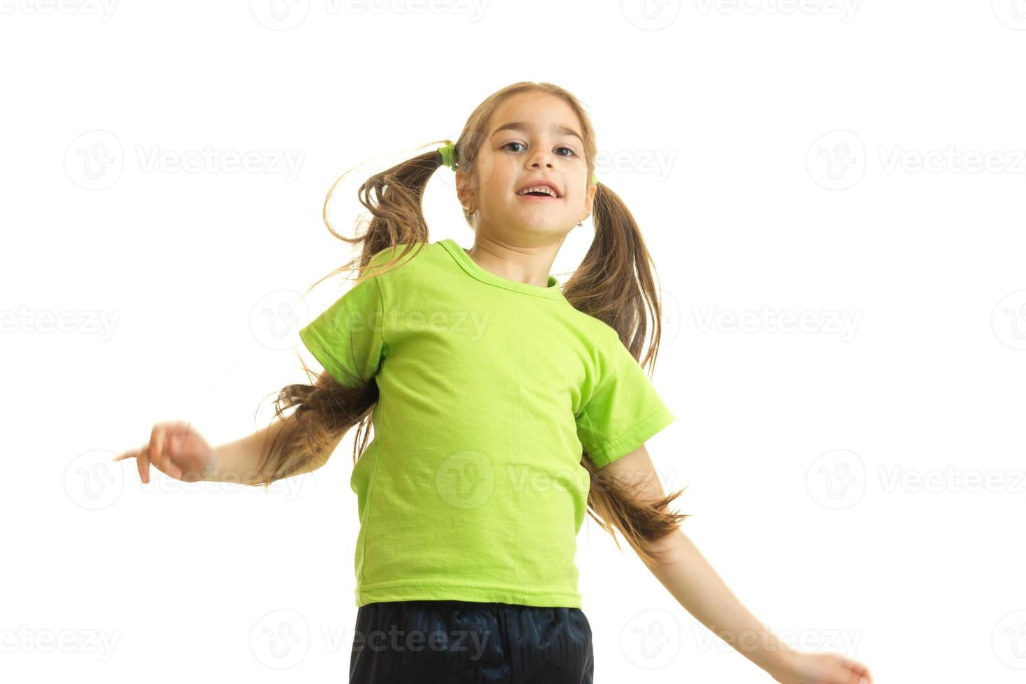 niña divertida en verde sonriendo al posar en la cámara foto