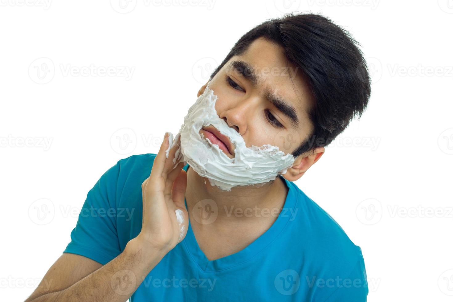 Portrait of a handsome guy with black hair causes shaving foam on your face closeup photo