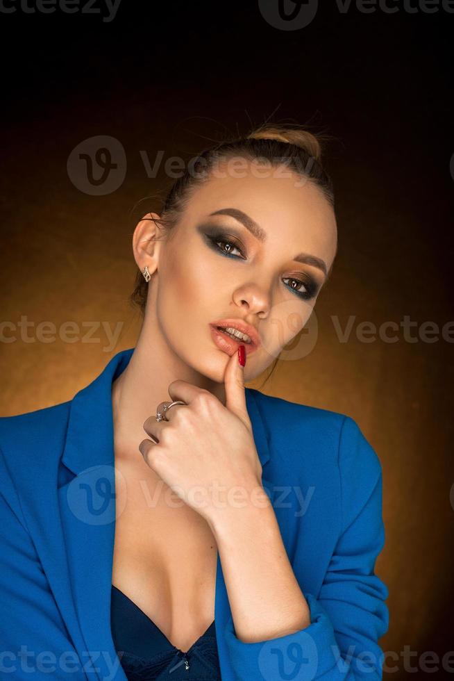 Beautiful young girl in blue jacket with beauty makeup in studio photo