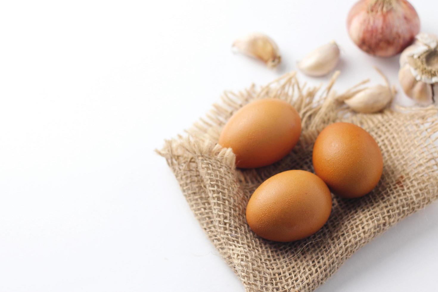 Three eggs laid on a sackcloth on a white table. photo