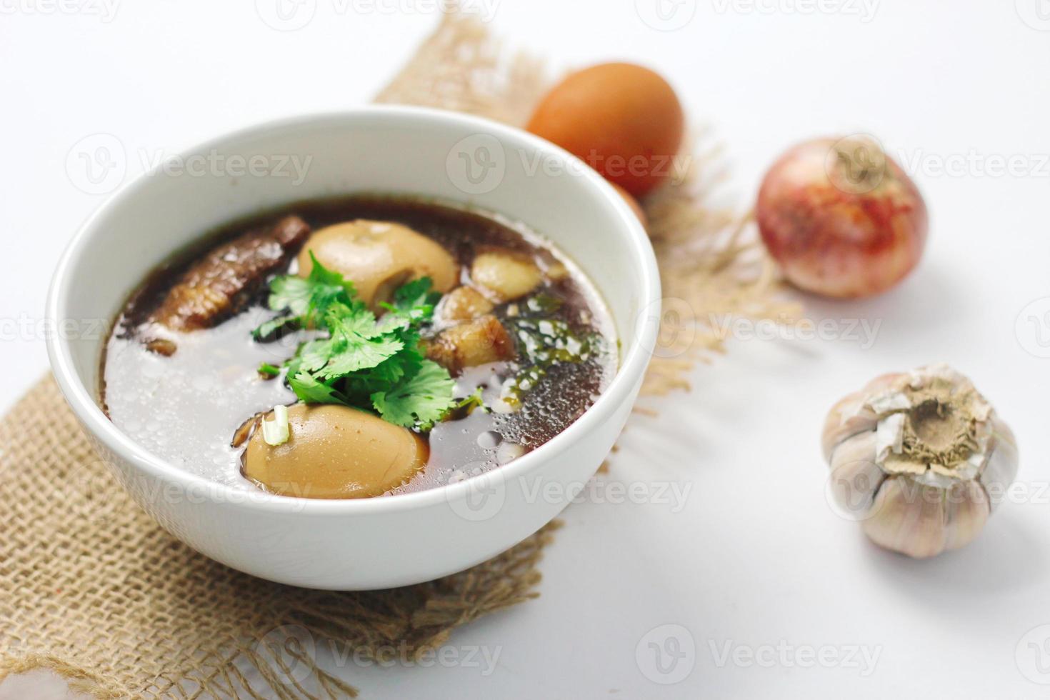 The Thai food we call Egg and Pork in Sweet Brown Sauce is served in a white cup. in a restaurant in Thailand photo