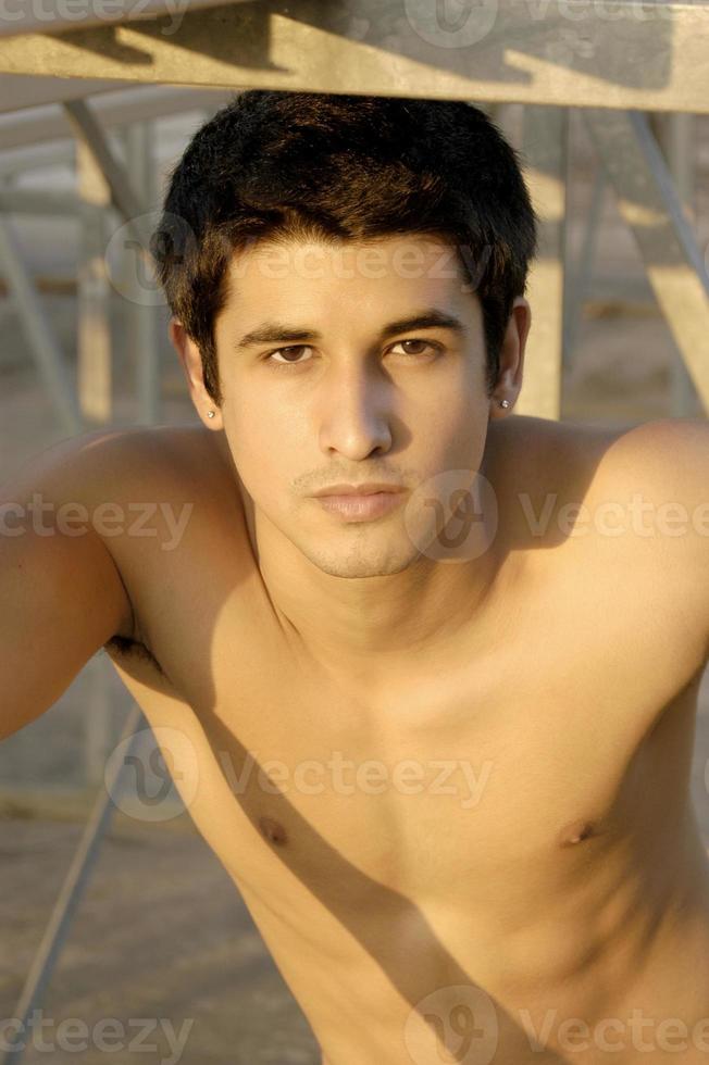un joven hispano guapo posa para un retrato de primer plano debajo de unas gradas. foto