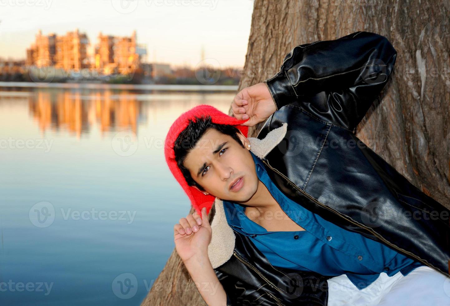 apuesto joven hispano en una pose sorpresa frente a un río en austin en un frío día de invierno. foto