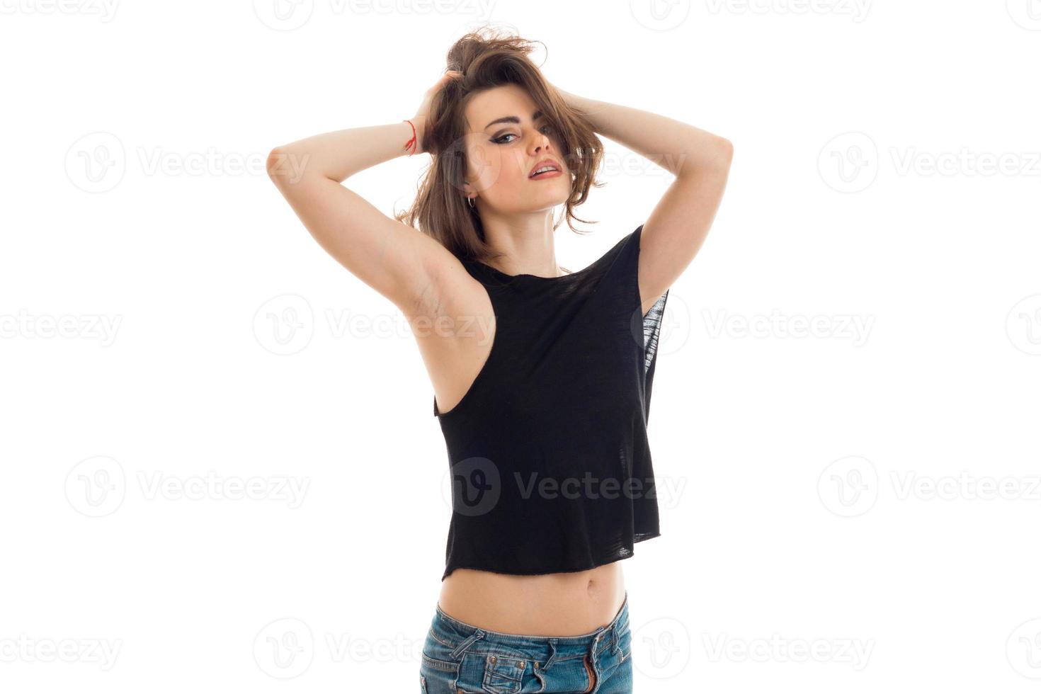 beautiful young girl in the black shirt keeps hair hands and erotic looks at camera photo