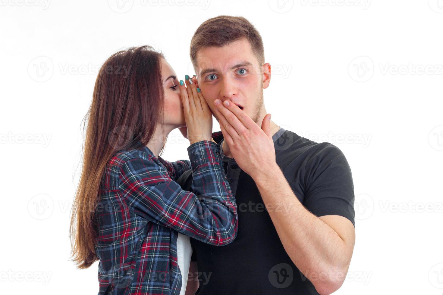 cute girl with long hair whispers a word in the ear of an amazing young guy who closed mouth hand photo