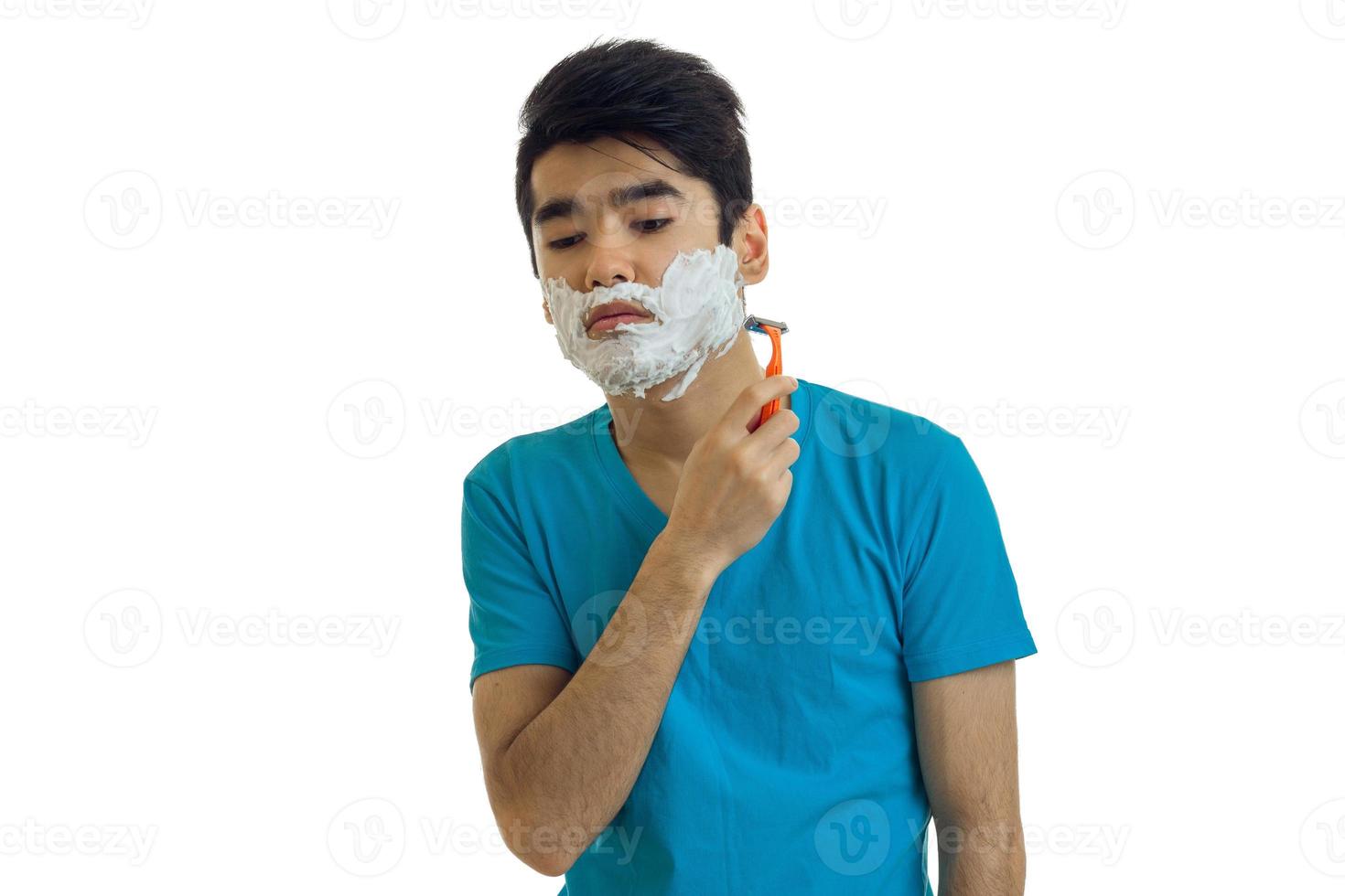 Sad young man in blue t-shirt shaving photo