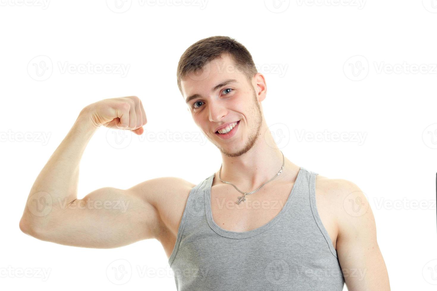 horizontal portrait of beautiful sports guy who smiles and shows his muscle on hand photo