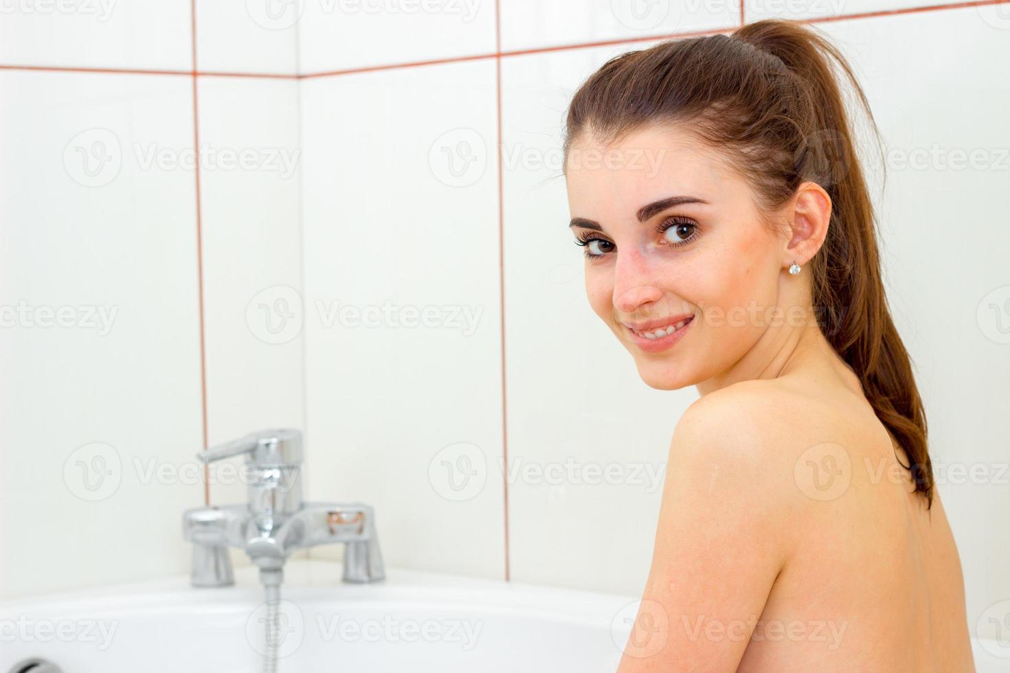 cute young girl bathed in the bathtub and smiles at the camera photo