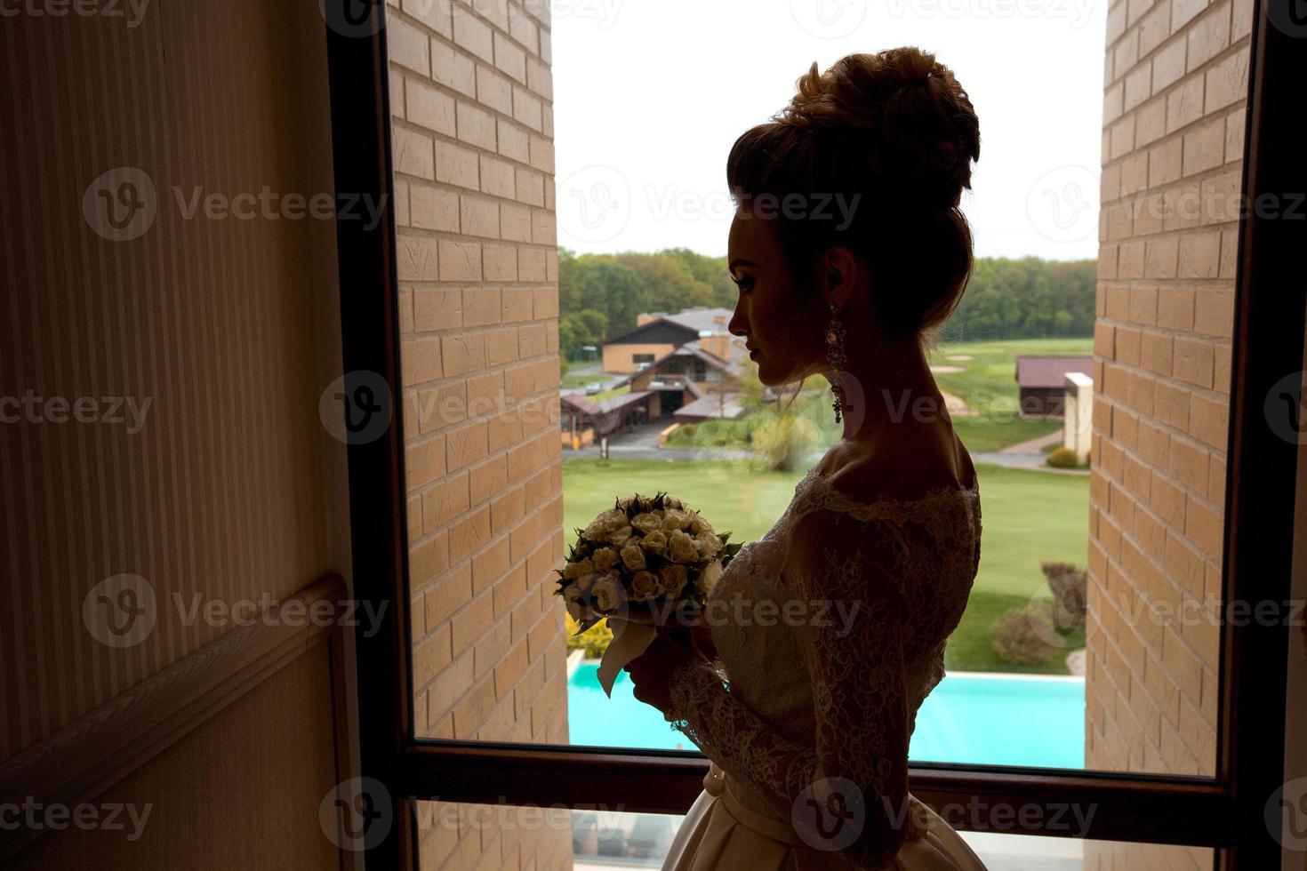 silhouette of young charming bride with bouquet of roses photo