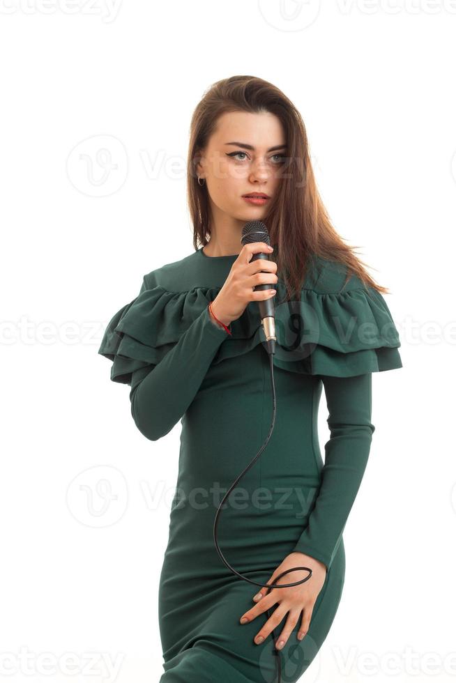 retrato vertical de una mujer hermosa con vestido verde canta un karaoke en el micrófono foto