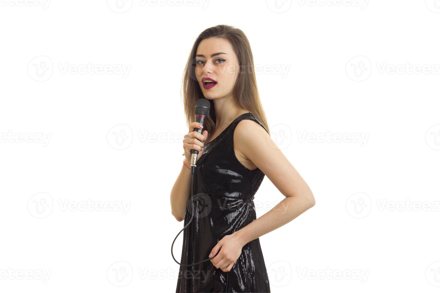 hermosa mujer morena en vestido negro cantando karaoke foto