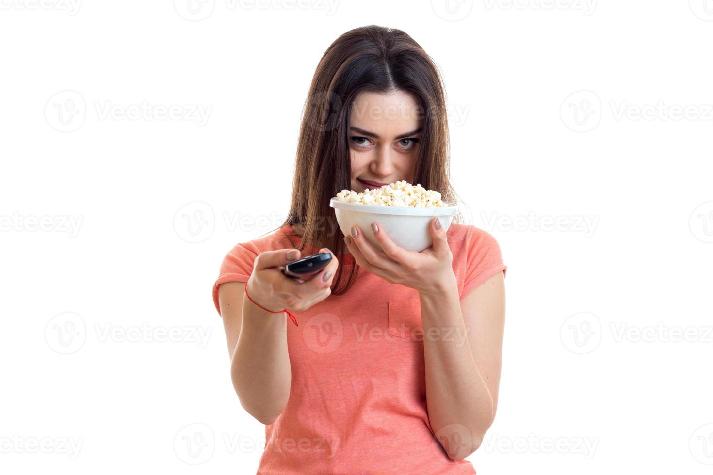 una chica joven y guapa come palomitas de maíz y ve la televisión foto