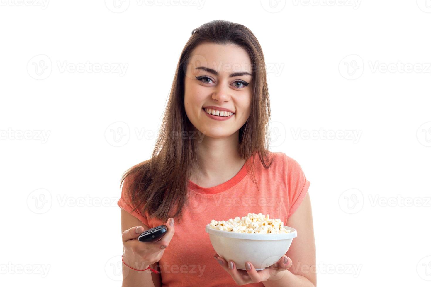 a cheerful girl with remote control from the tv and popcorn smiles photo