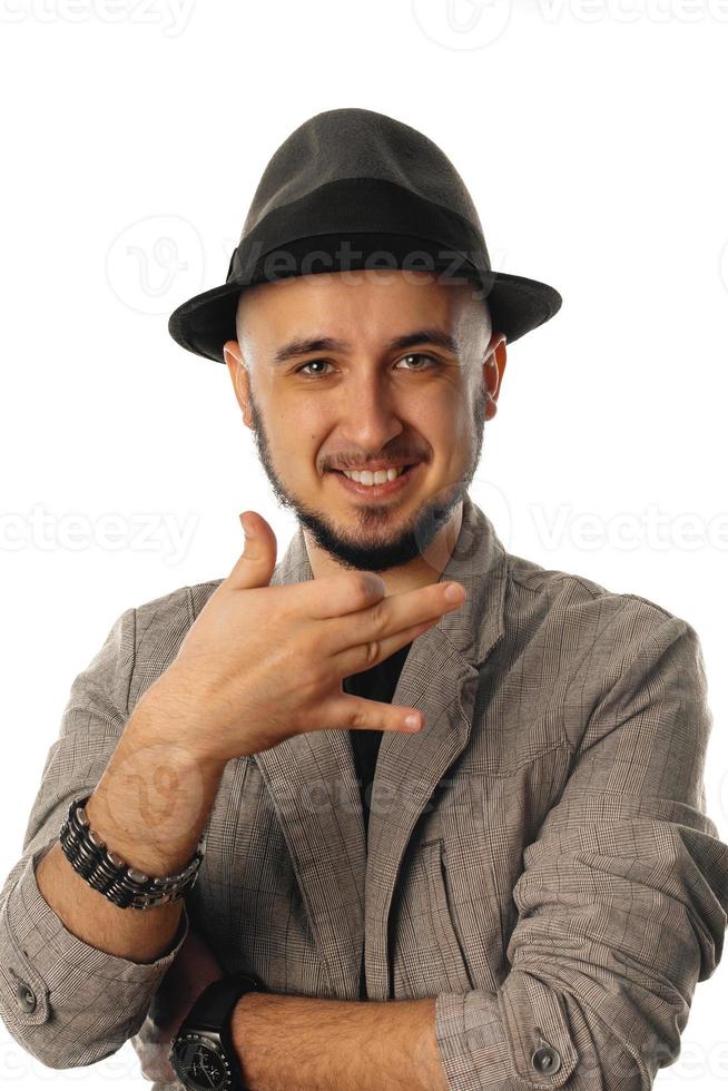 retrato vertical de un joven alegre sin afeitar con sombrero y chaqueta mirando a la cámara y sonriendo foto