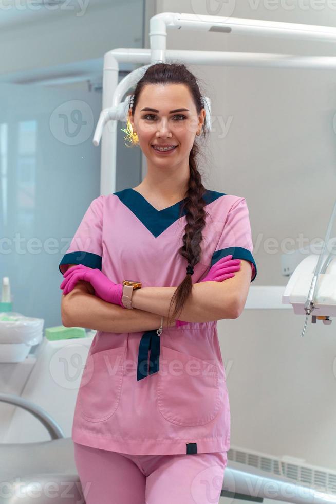 beautiful dentis in pink uniform smiles on camera photo