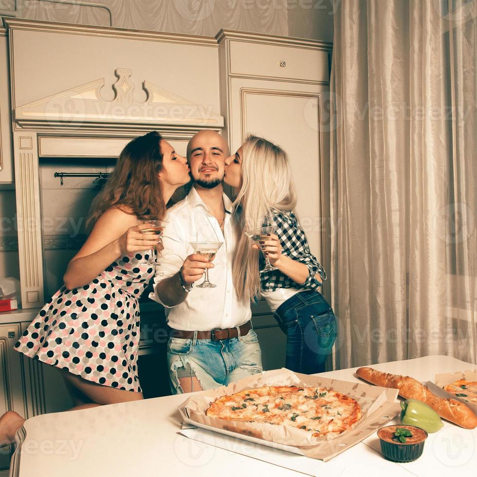 Two beautiful ladies kisses a boy at home party photo