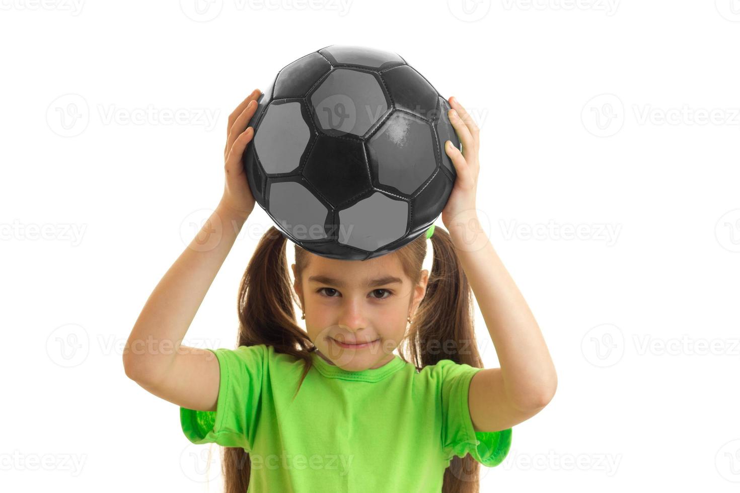 pretty little girl in green shirt with soccer ball in hands photo