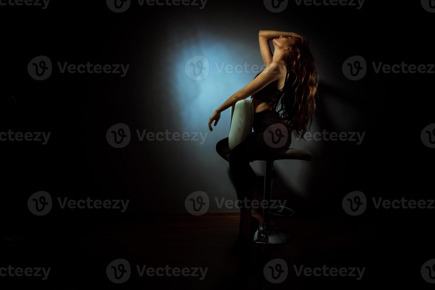 Gorgeous lady with curly hairstyle in dark studio photo