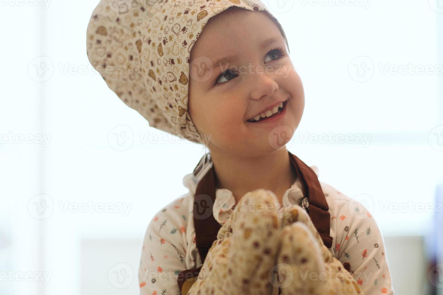 portrait of cute little homecook girl in white kitchen. photo