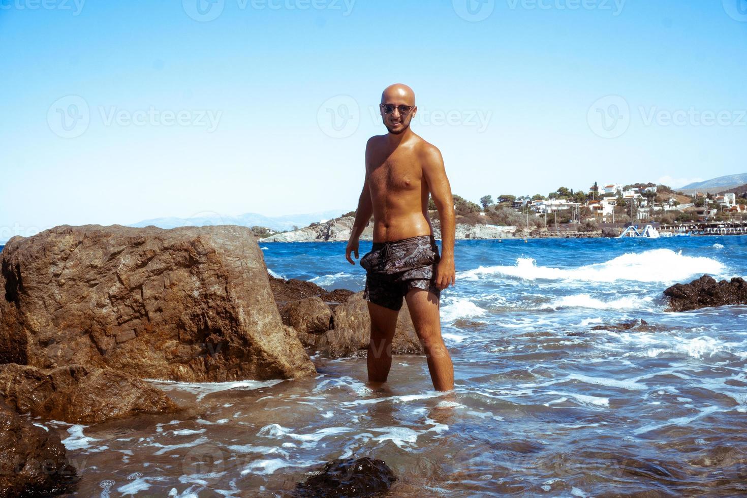 young sexy guy on the Rocky seashore photo