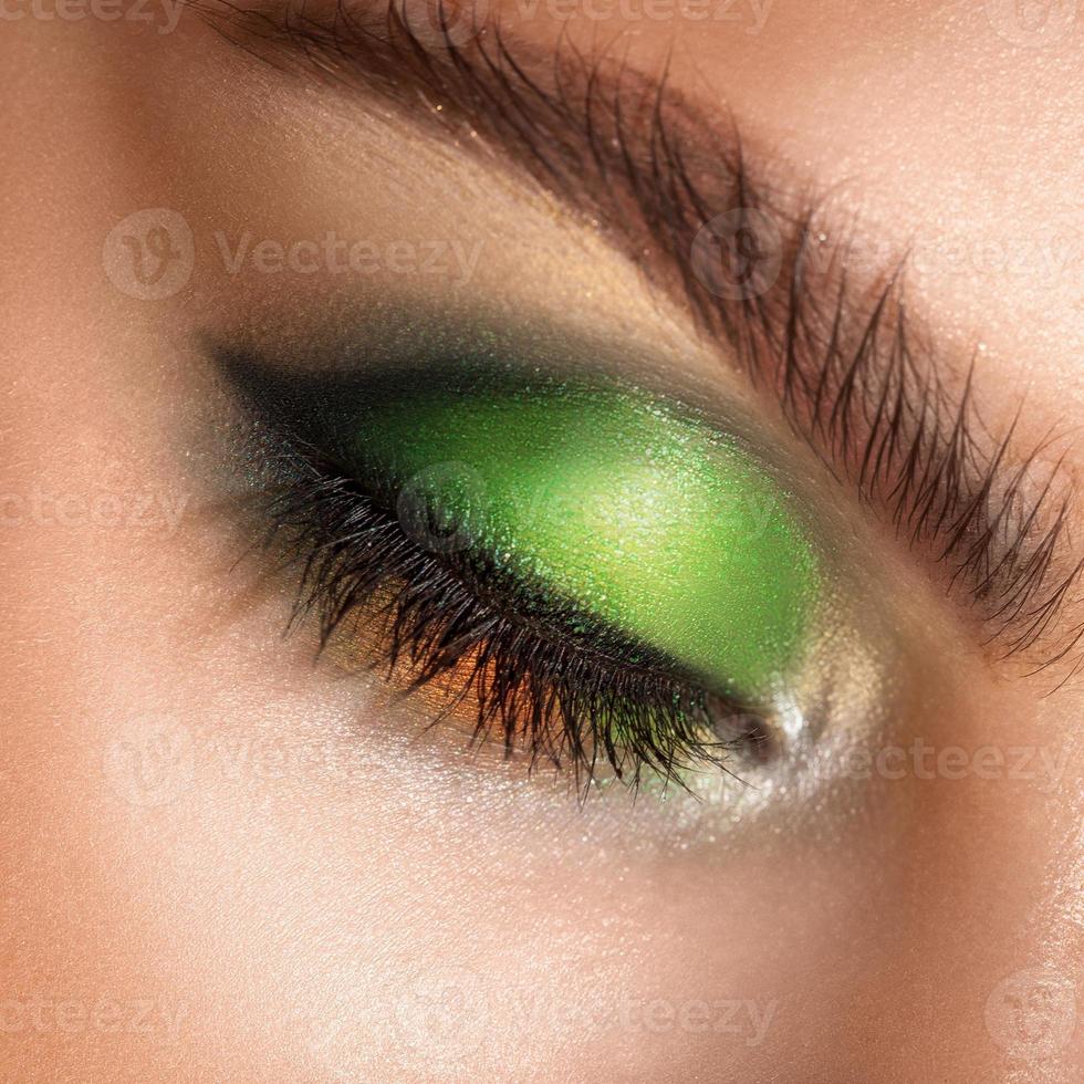 macro photo of closed eyes with professional green colors makeup