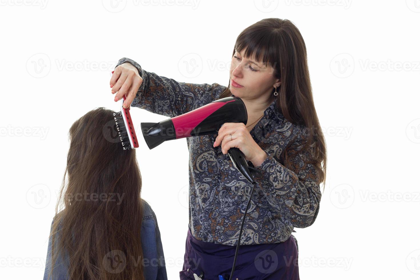 estilista de mujer adulta hace un peinado a una niña con el pelo largo foto