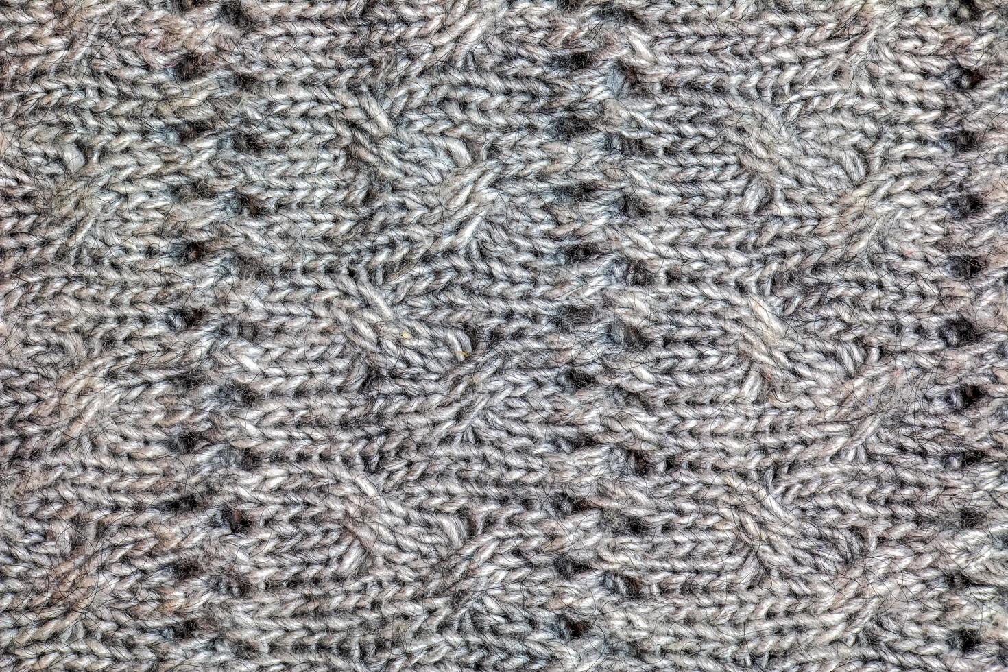 Gray knitted handmade sweater background. The texture of the surface of the woolen jersey made of yarn, close-up. Image for the background. Wool carpet or sweater. Gray texture. Modern design. photo