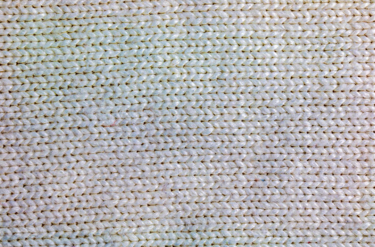 The texture of a large knit sweater or scarf. Knitted background with a relief pattern. Wool hand or machine knitting. Fabric background. photo