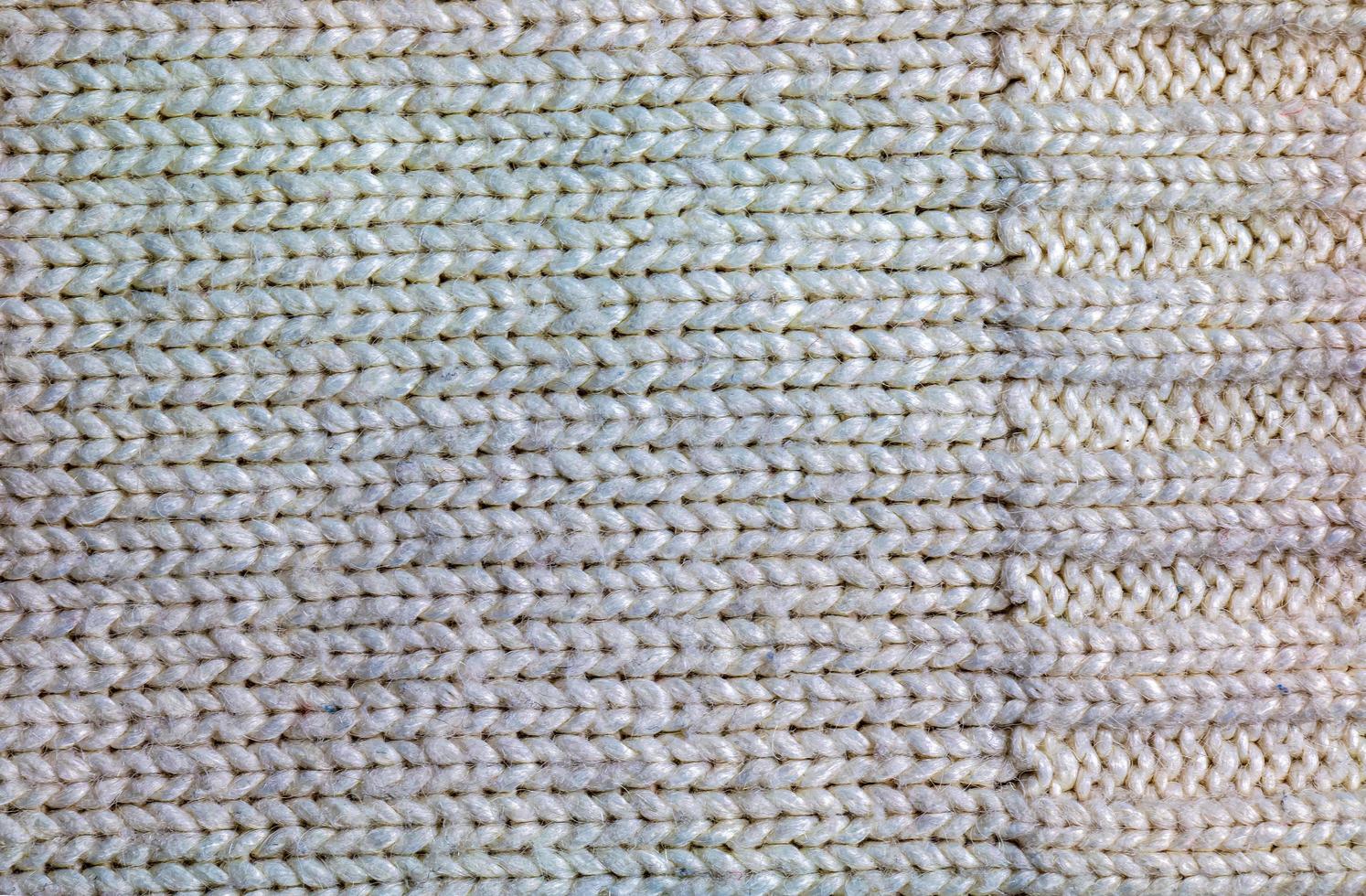 The texture of a large knit sweater or scarf. Knitted background with a relief pattern. Wool hand or machine knitting. Fabric background. photo