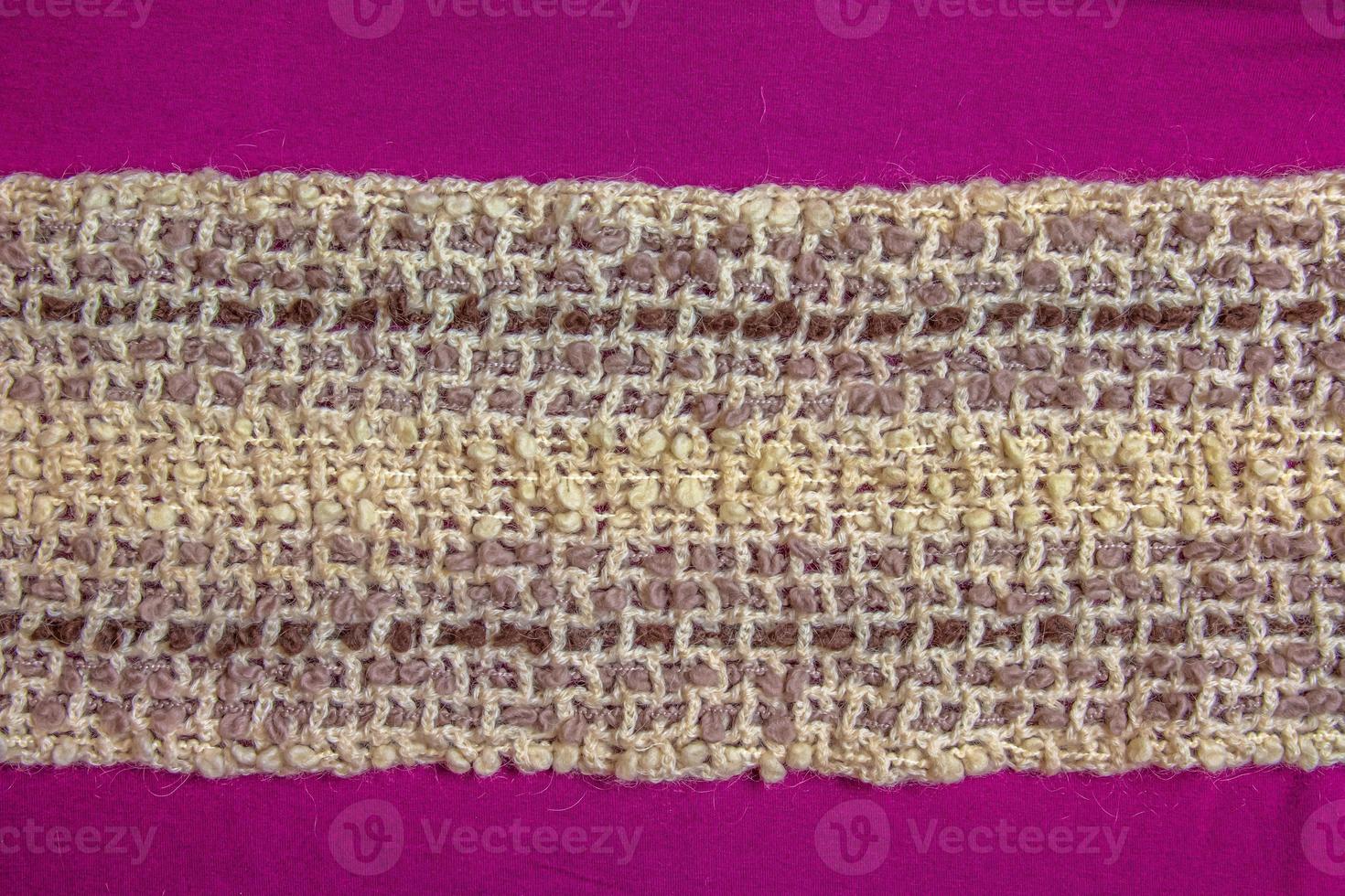 Warm beige woolen scarf on a lilac-burgundy background photo