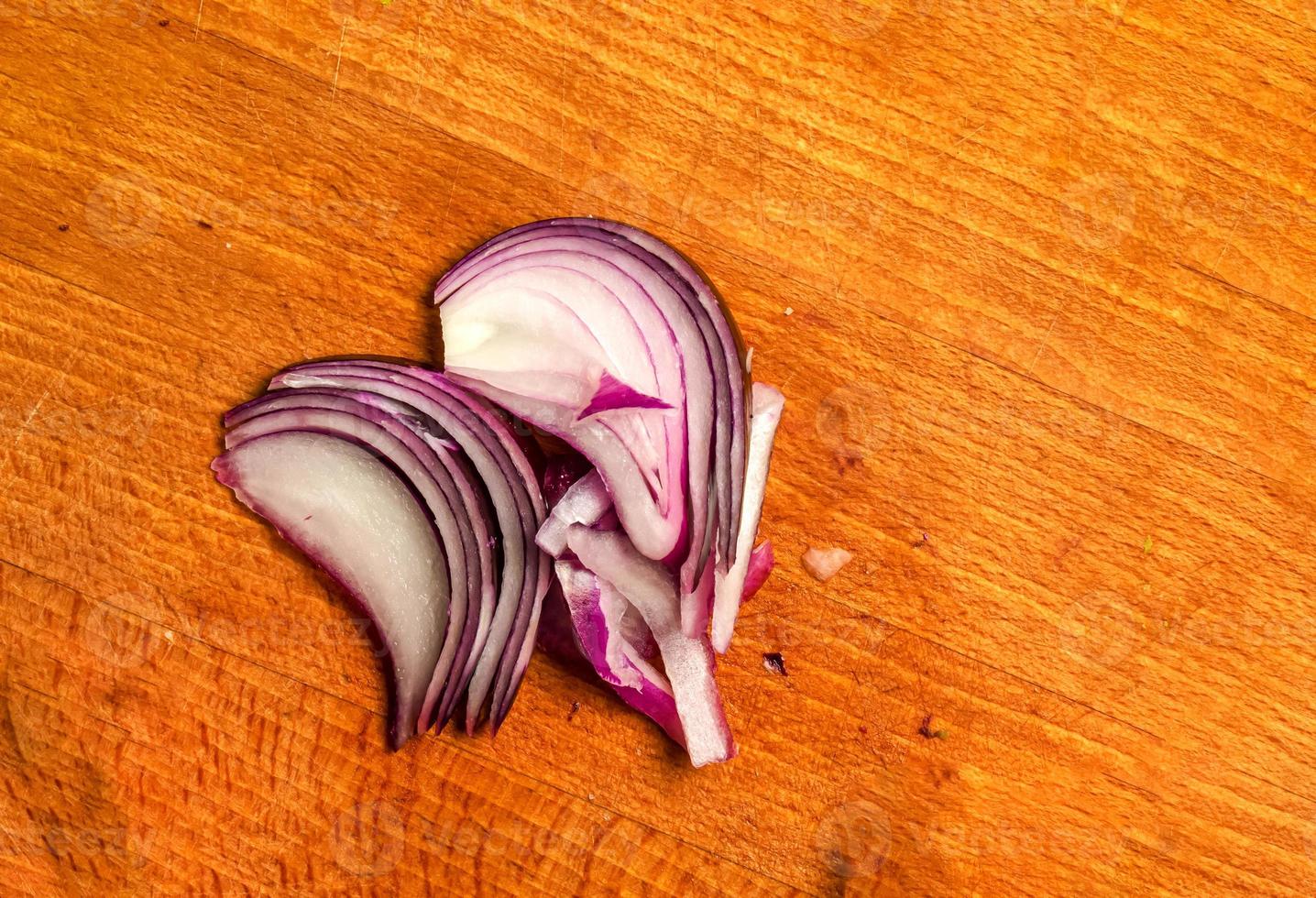 Purple onion thinly sliced on a wooden board. Top view of juicy onion slices. photo