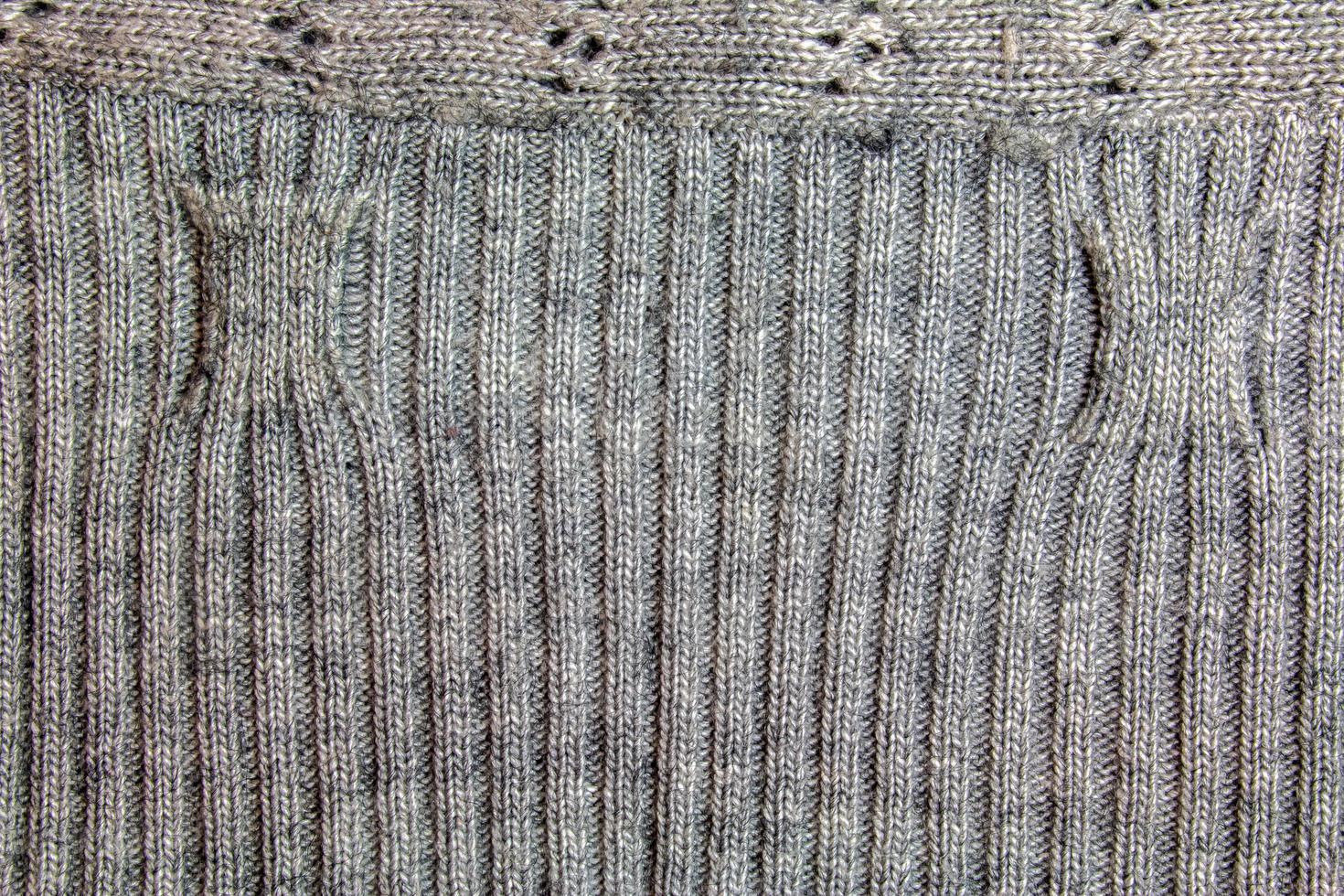 Gray knitted handmade sweater background. The texture of the surface of the woolen jersey made of yarn, close-up. Image for the background. Wool carpet or sweater. Gray texture. Modern design. photo