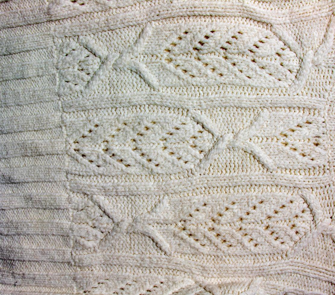 The texture of a large knit sweater or scarf. Knitted background with a relief pattern. Wool hand or machine knitting. Fabric background. photo