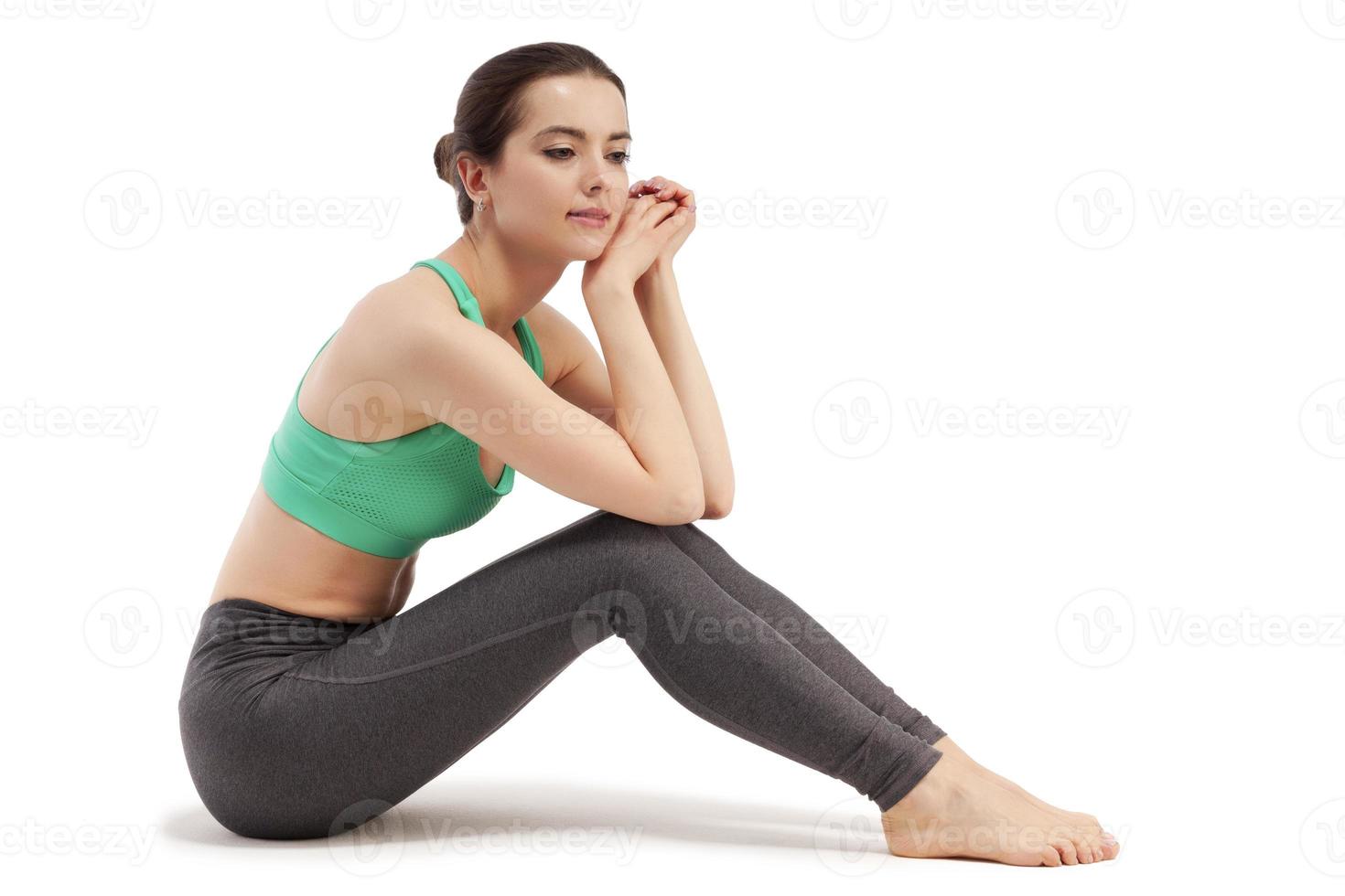 Young woman sitting on floor wearing sports outfit. Isolated on white background photo