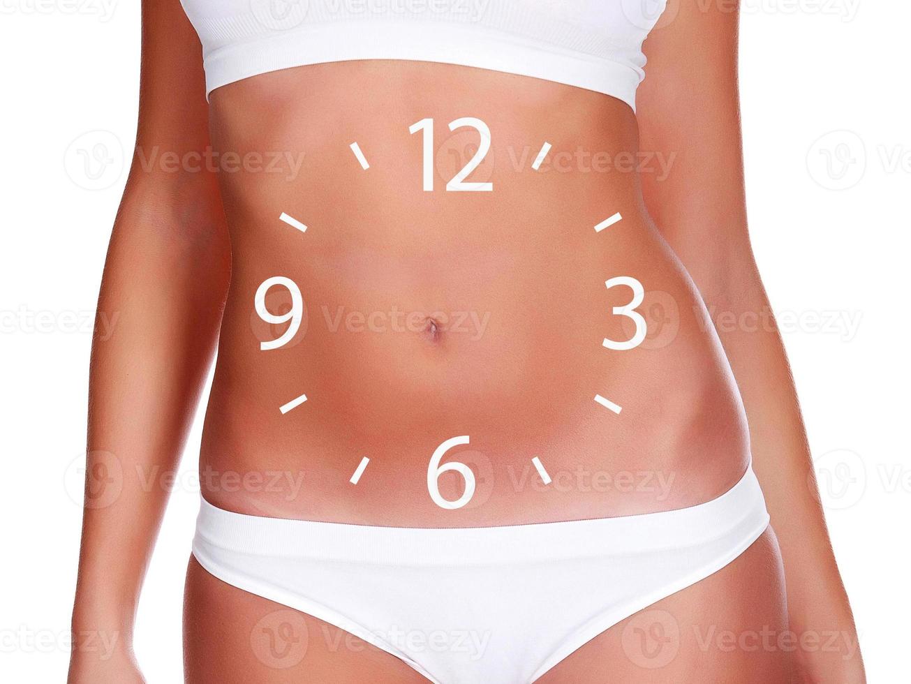 Slim woman body with a clock face on her belly on white background, isolated photo