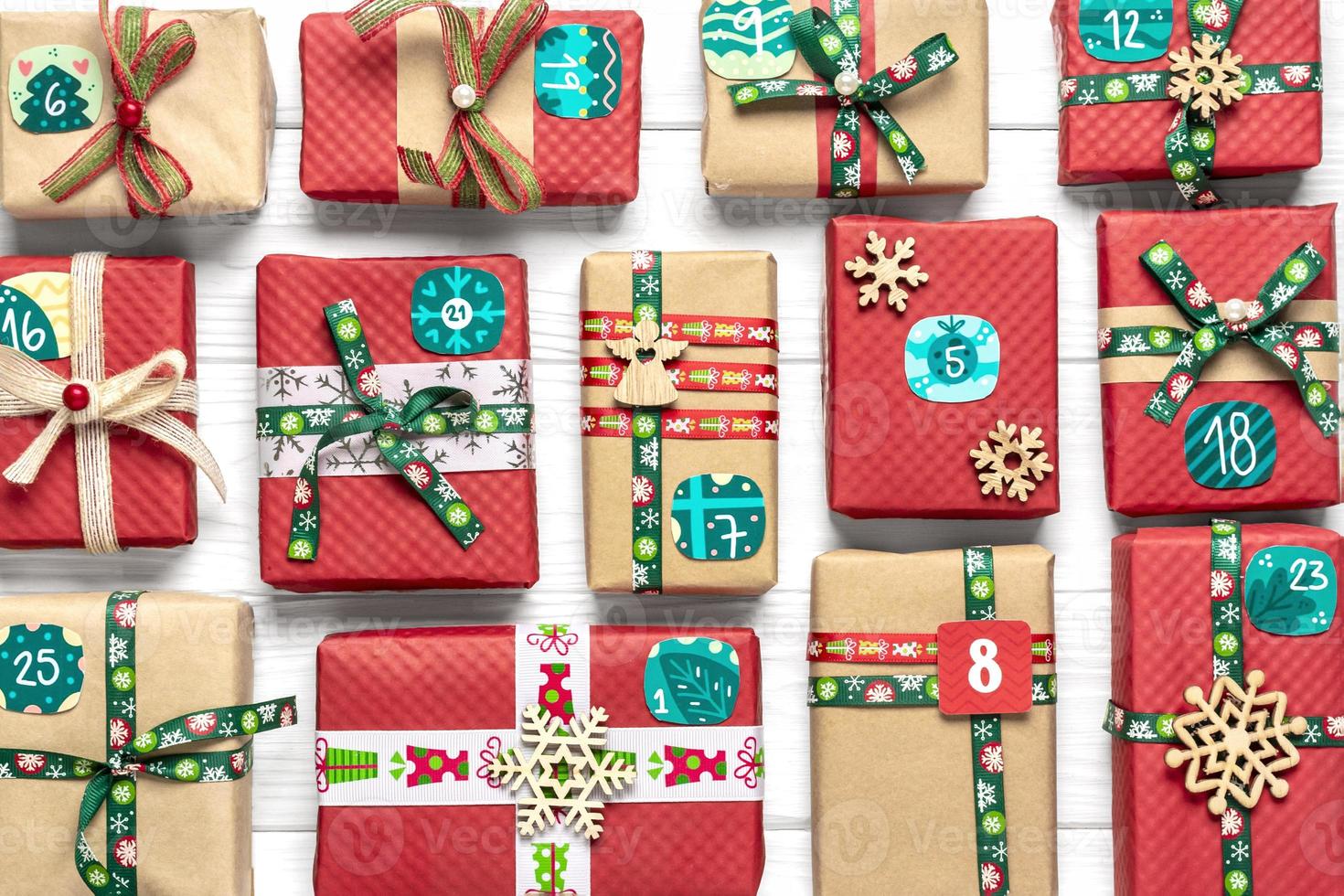 cajas de regalo rojas y verdes envueltas a mano decoradas con cintas, copos de nieve y números, adornos navideños y decoración en mesa blanca concepto de calendario de adviento de navidad vista superior tarjeta de vacaciones plana foto