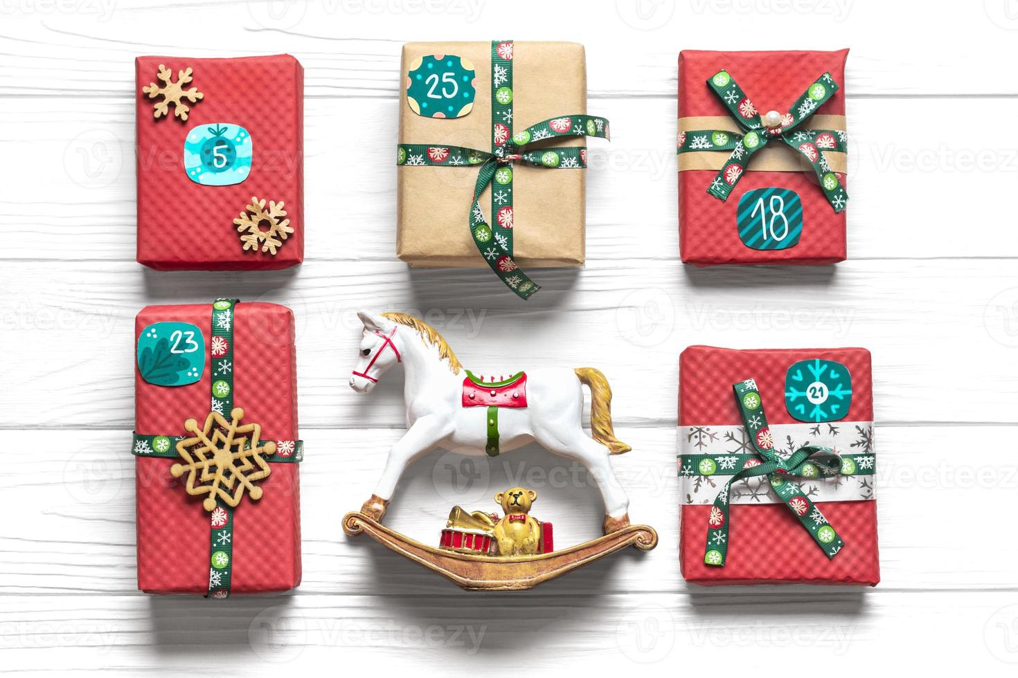 cajas de regalo rojas y verdes envueltas a mano decoradas con cintas, copos de nieve y números, adornos navideños y decoración en mesa blanca concepto de calendario de adviento de navidad vista superior tarjeta de vacaciones plana foto