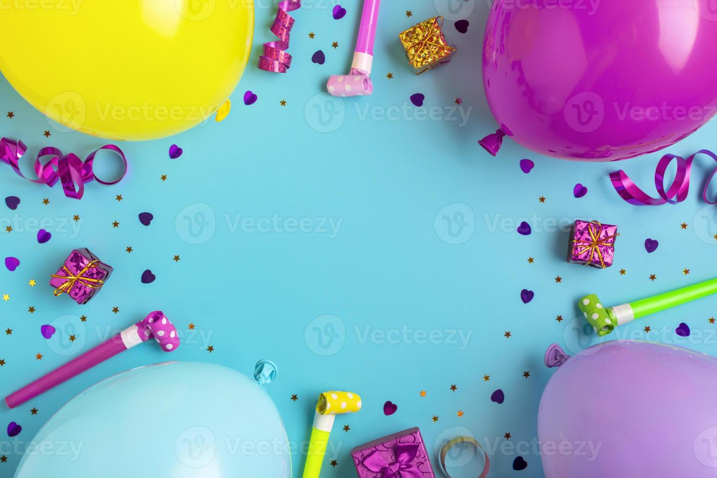 Colorful party frame with red gift box with various party confetti, balloons, streamers, pokers and decorations on blue background. Holiday card Flat lay Top view Happy Birthday party concept photo