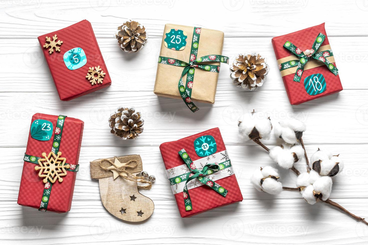 Handmade wrapped red, green gift boxes decorated with ribbons, snowflakes and numbers, Christmas decorations and decor on white table Xmas advent calendar concept Top view Flat lay Holiday card photo