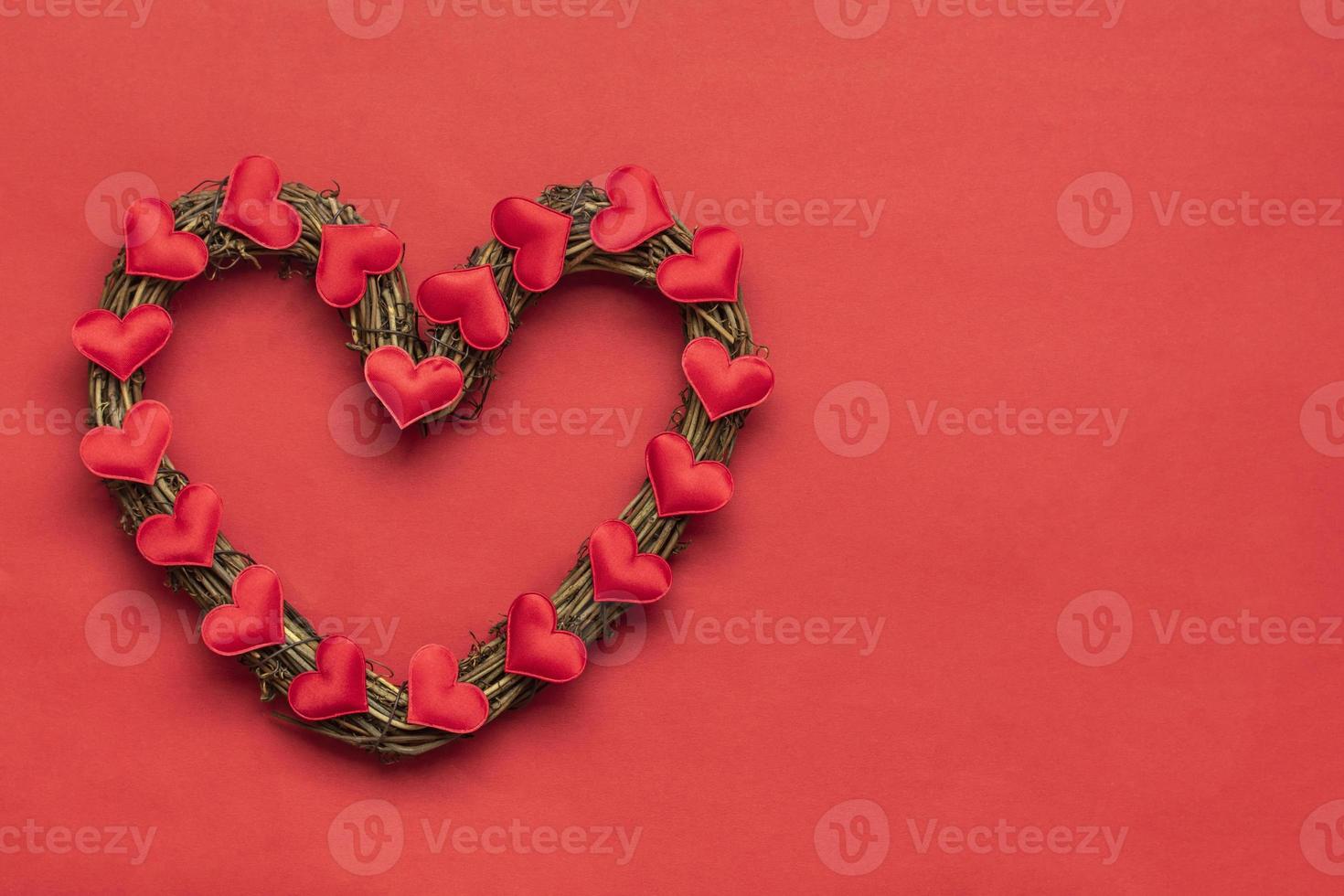 corona de planta de ratán en forma de corazón decorada con corazones rojos sobre fondo rojo vista superior plana tarjeta de vacaciones feliz día de san valentín, concepto de amor espacio de copia foto