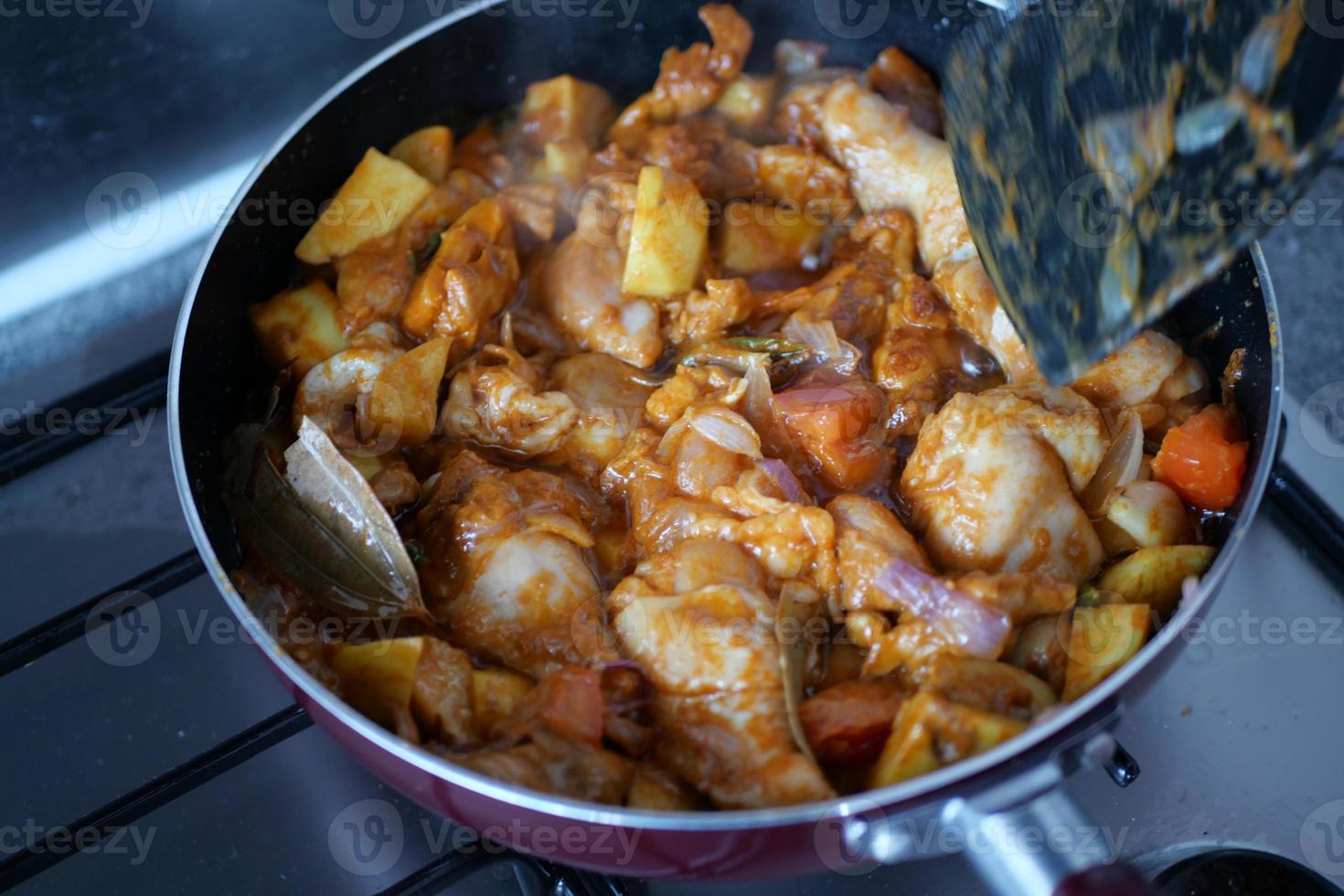 cooking chicken curry in a cooking pan photo