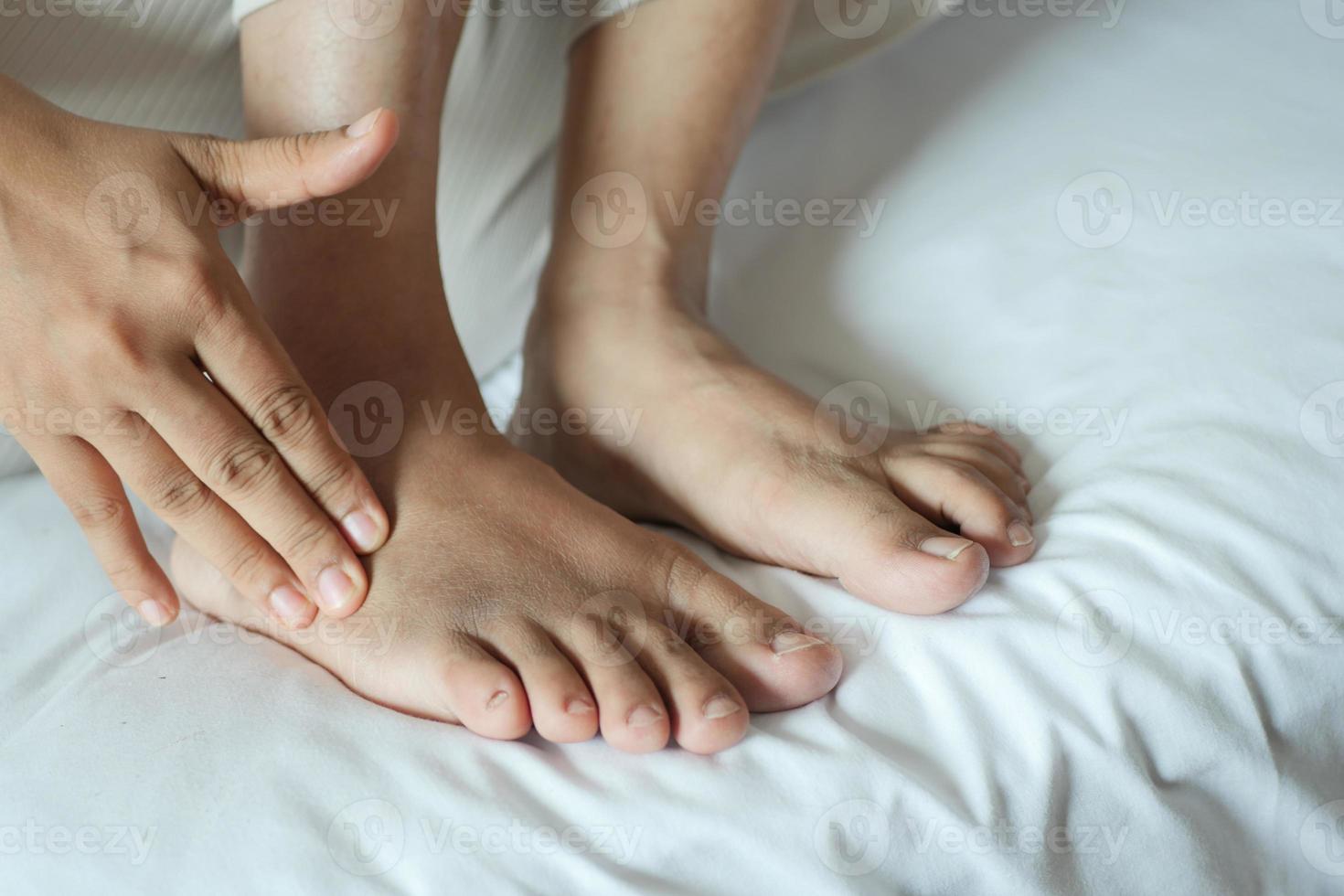 young women suffering feet pain sitting on bed photo