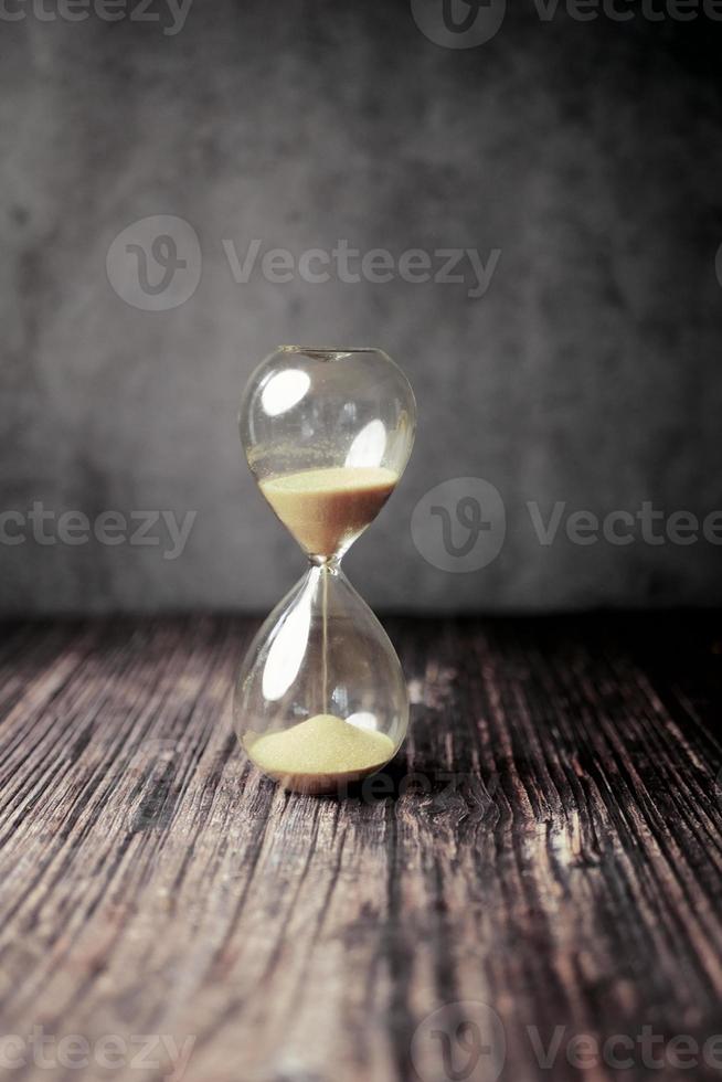 reloj de arena en la mesa, arena que fluye a través del bulbo del reloj de arena foto
