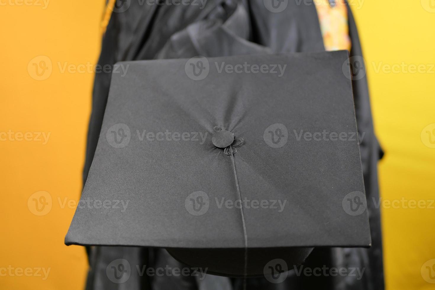 Student hold hats in hand during commencement success on yellow background photo