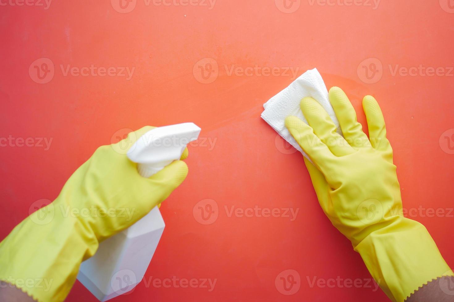 hand in yellow rubber gloves holding spray bottle cleaning table photo