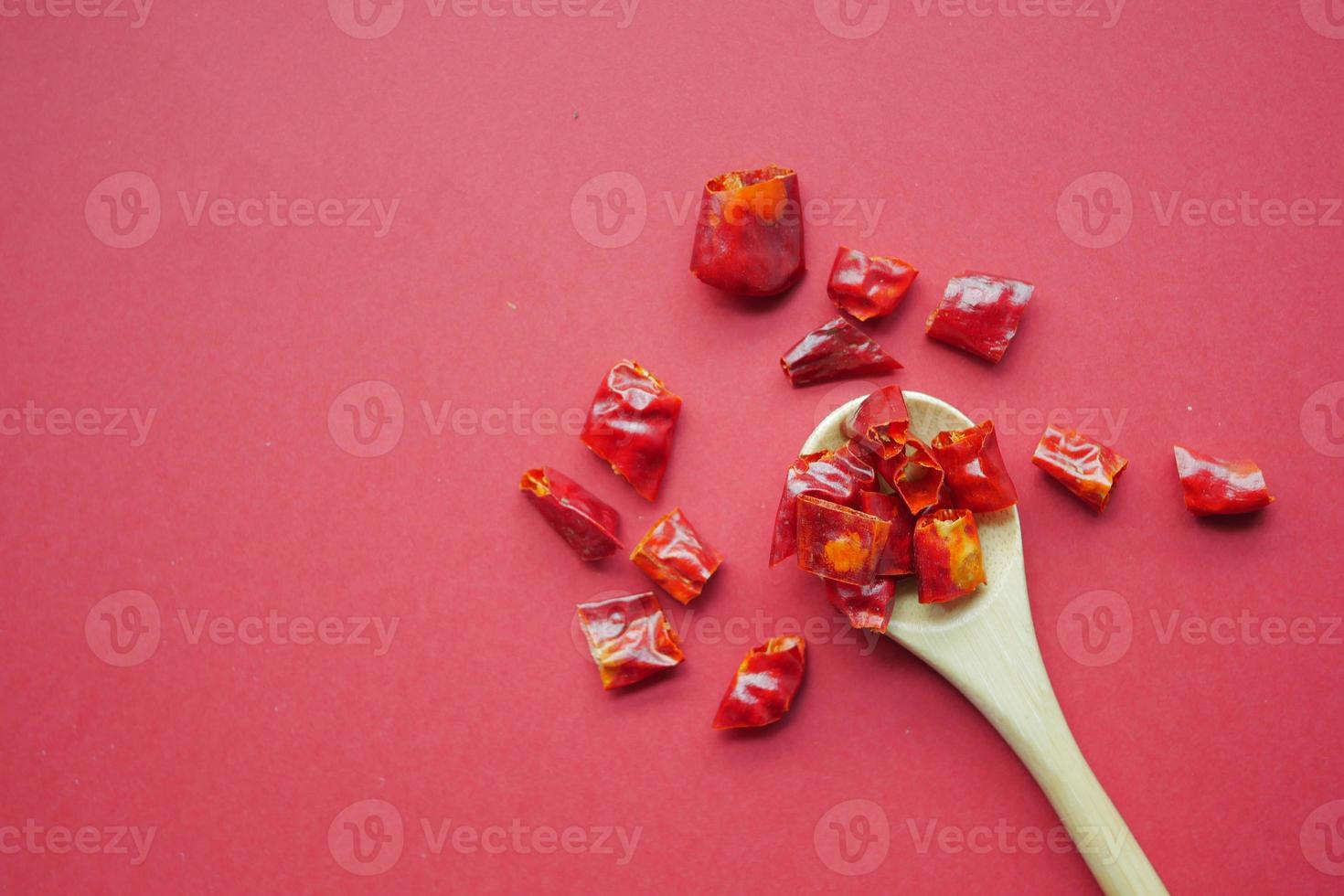hojuelas de chile rojo derramándose sobre fondo rojo foto