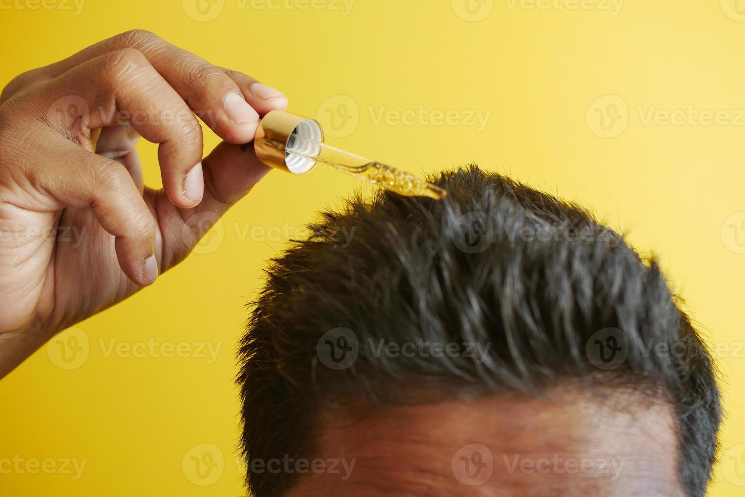 young men applying essential oils on his hair photo