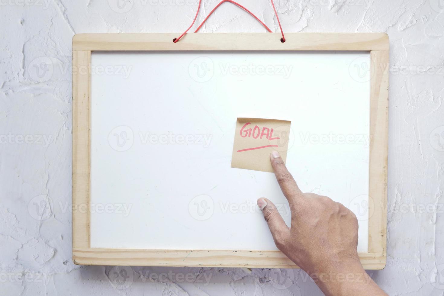 putting a sticky note with goal word on a white board photo