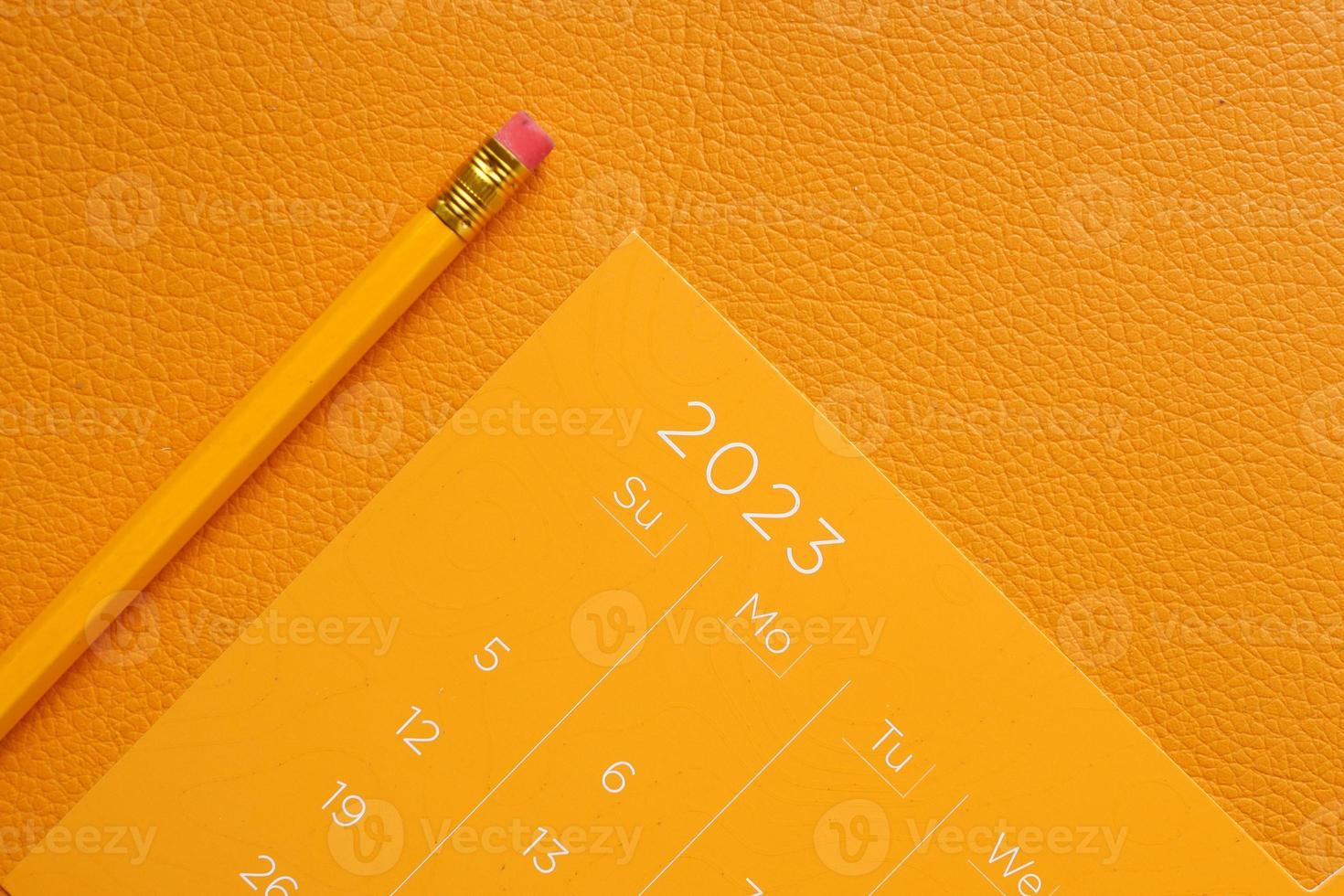 orange color 2023 year calendar and a pencil on table photo